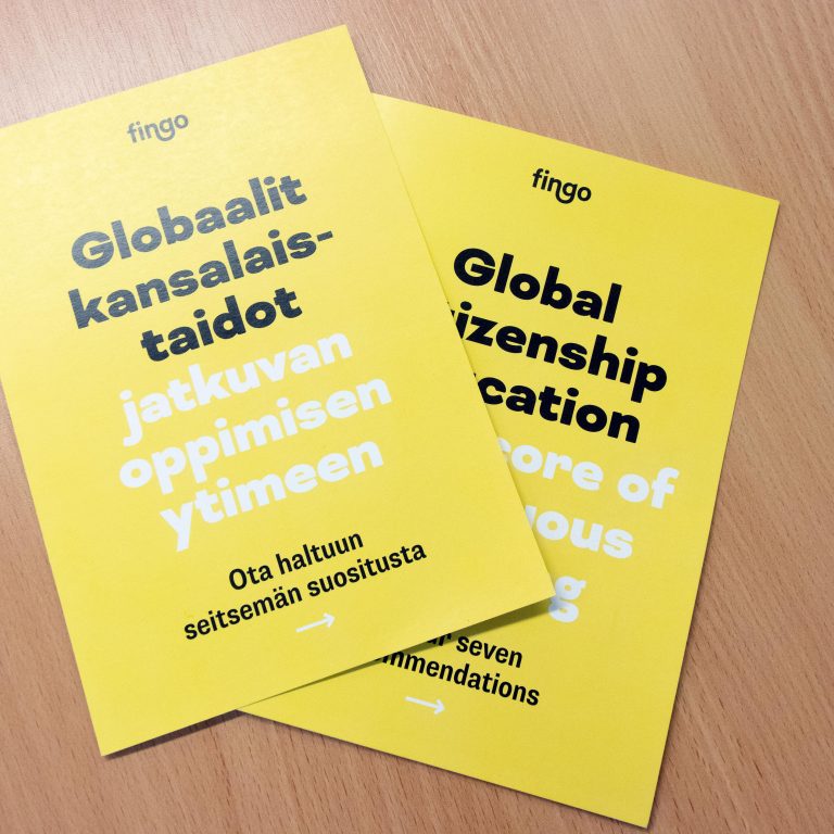 Kaksi Fingon keltaista Globaalit kansalaistaidot -esitettä puisella pöydällä.