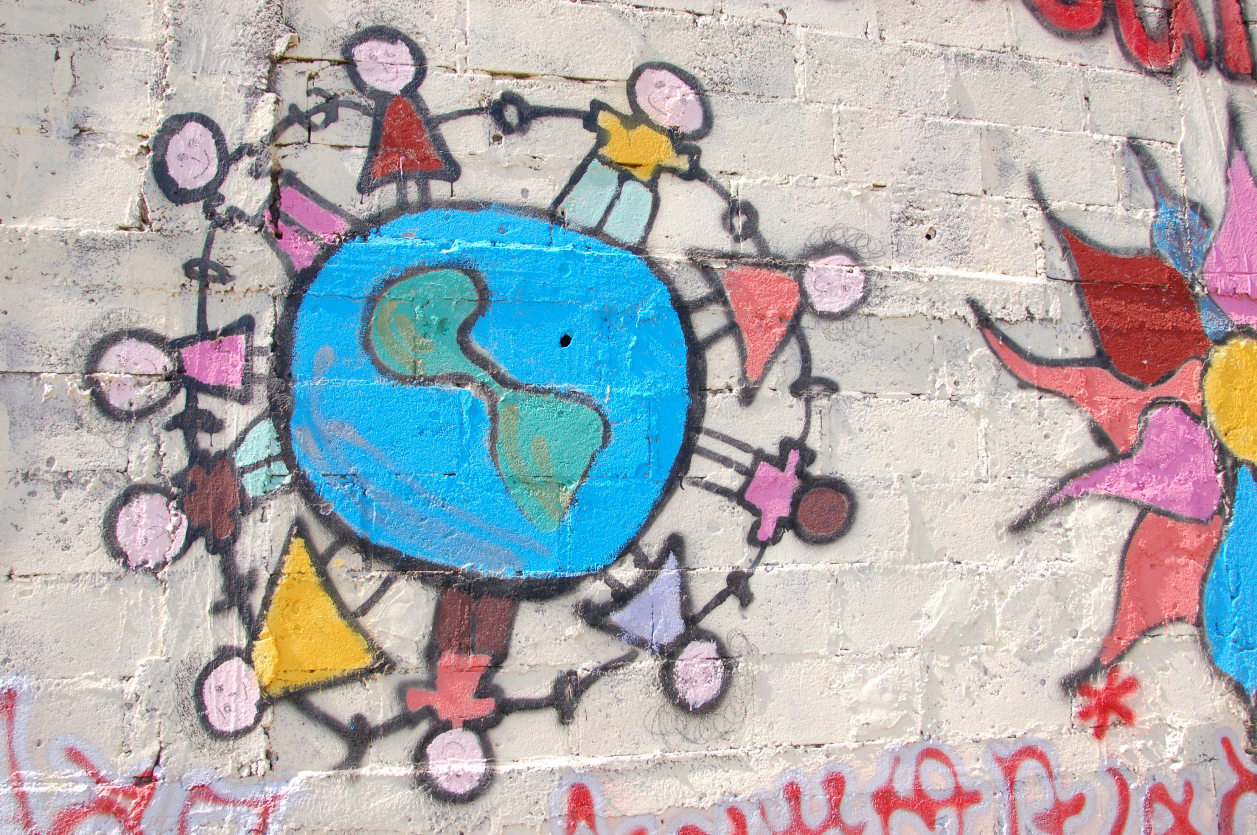 Graffititaidetta: maapallo, jonka ympärillä ihmiset pitävät toisiaan käsistä kiinni.